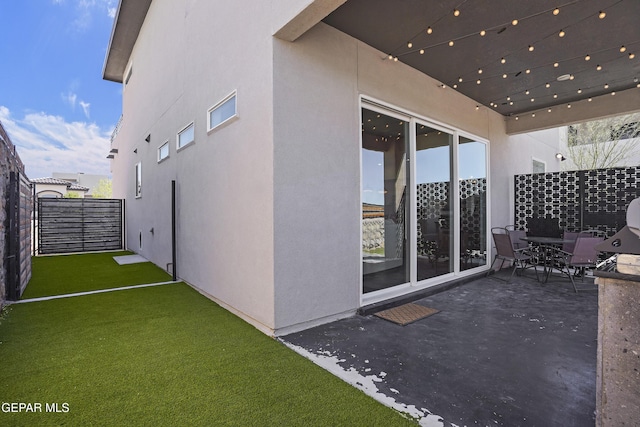 exterior space featuring a lawn, fence, stucco siding, and a patio area