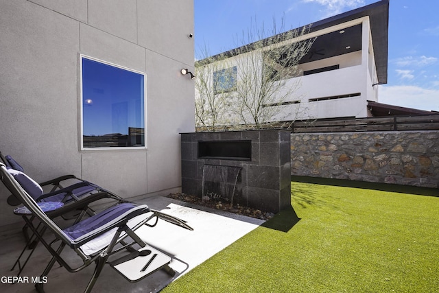 rear view of house featuring stucco siding, a yard, and a patio