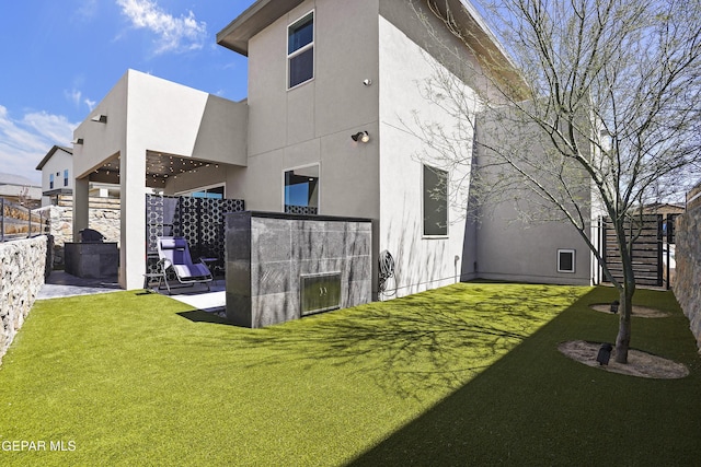 back of property with stucco siding, fence, and a lawn