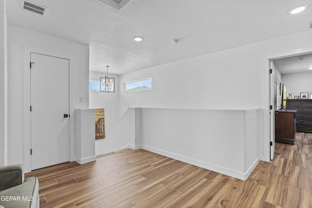 foyer entrance featuring baseboards, visible vents, wood finished floors, and a textured ceiling