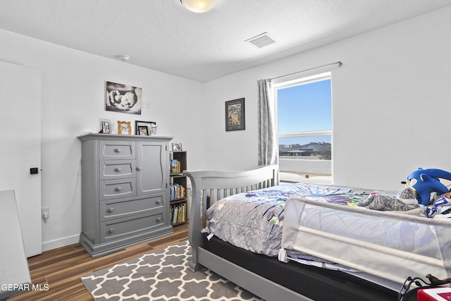 bedroom with visible vents, baseboards, and dark wood-type flooring