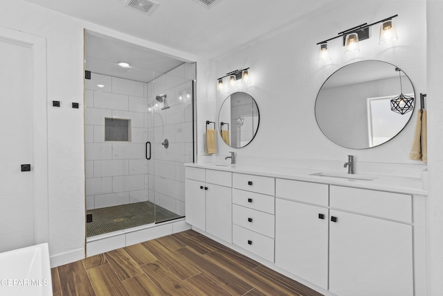 full bathroom featuring wood finished floors, visible vents, a shower stall, and a sink