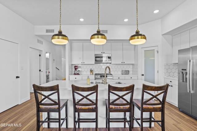 kitchen featuring pendant lighting, stainless steel appliances, light countertops, and a sink