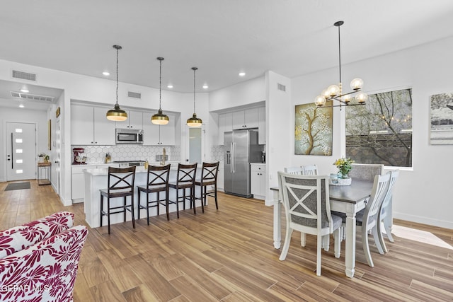 dining room featuring visible vents, recessed lighting, light wood-style flooring, and a notable chandelier