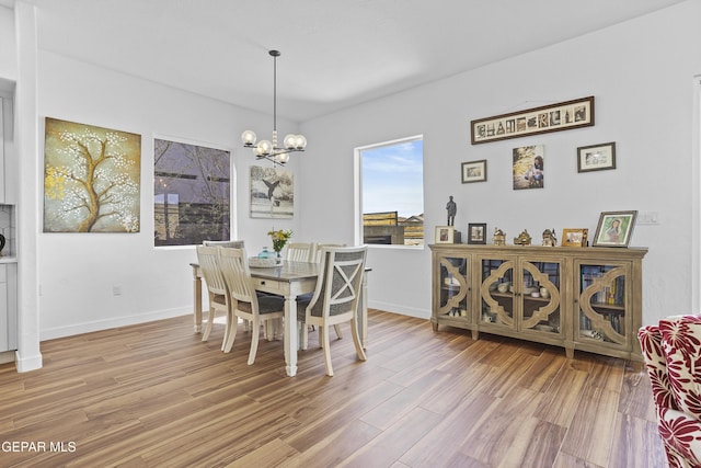 dining space with a chandelier, baseboards, and light wood-style floors