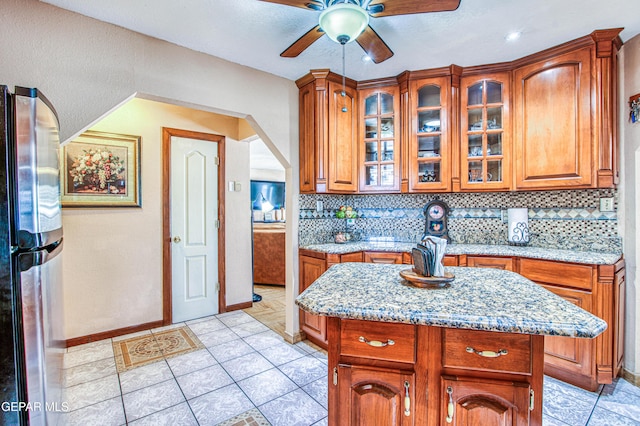 916 Mike Maros St, Fabens, TX 79838 - kitchen featuring brown cabinetry, ceiling fan, decorative backsplash, and freestanding refrigerator