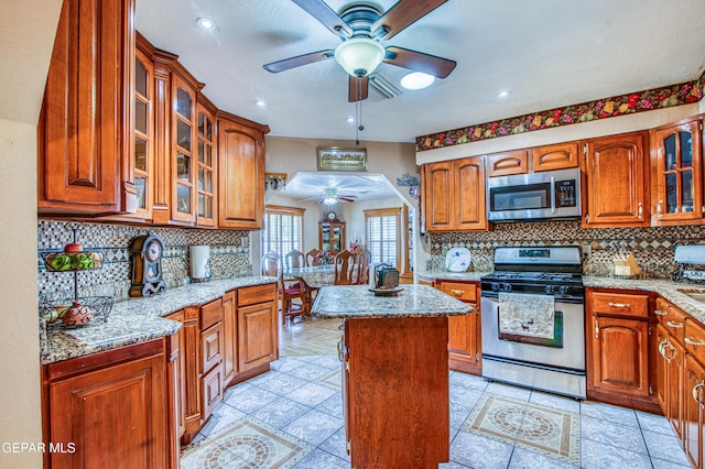 916 Mike Maros St, Fabens, TX 79838 - kitchen featuring tasteful backsplash, appliances with stainless steel finishes, ceiling fan, a center island, and light stone countertops