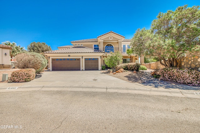mediterranean / spanish house with a tiled roof, an attached garage, driveway, and stucco siding