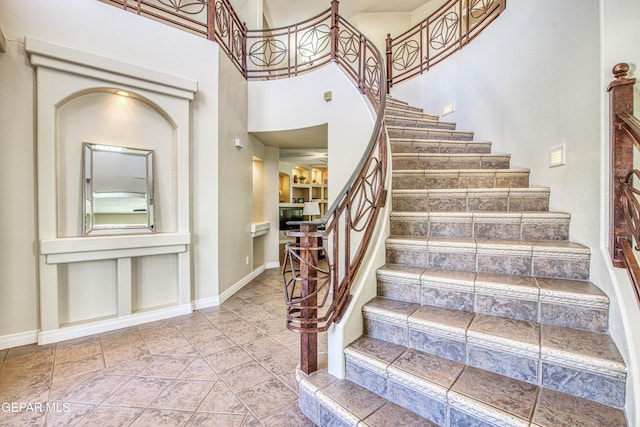 stairway featuring baseboards and a towering ceiling