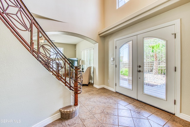 foyer with stairway, arched walkways, plenty of natural light, and french doors