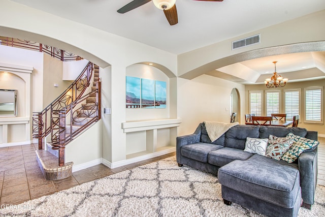 living area with visible vents, baseboards, stairway, arched walkways, and ceiling fan with notable chandelier