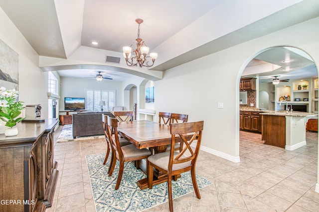 dining area featuring visible vents, arched walkways, ceiling fan with notable chandelier, and a tray ceiling