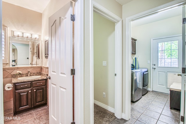 bathroom with tile patterned flooring, tasteful backsplash, washing machine and dryer, vanity, and baseboards