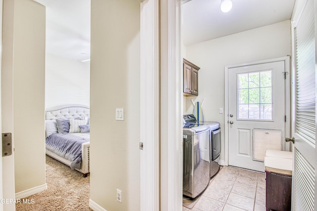 laundry room with cabinet space, light tile patterned floors, baseboards, and washer and clothes dryer