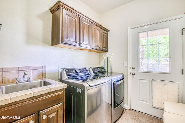 laundry area with a sink, cabinet space, light tile patterned floors, and washing machine and clothes dryer