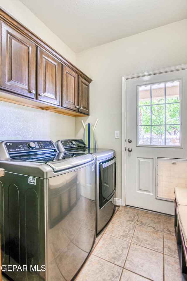 washroom featuring washing machine and clothes dryer, light tile patterned flooring, and cabinet space