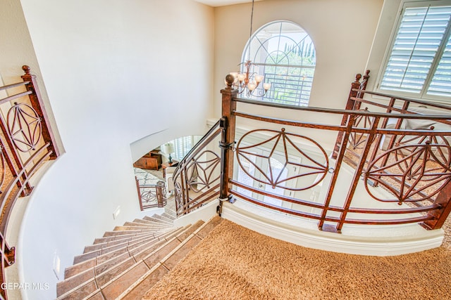 stairway with plenty of natural light and a notable chandelier