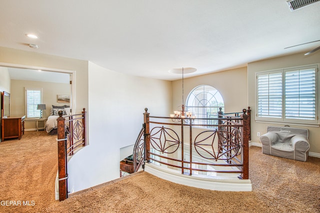 stairs with an inviting chandelier, carpet floors, baseboards, and visible vents