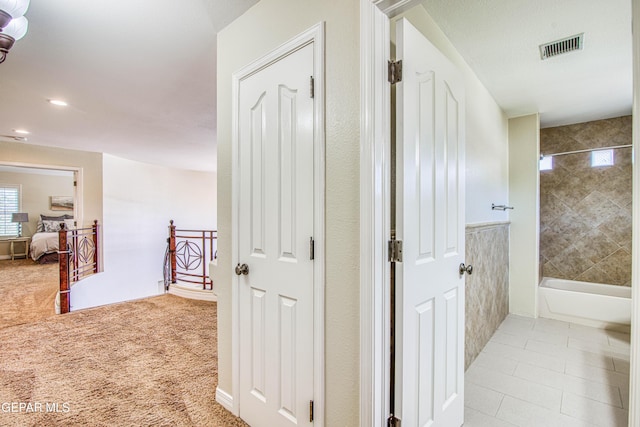 hall featuring light carpet, an upstairs landing, and visible vents