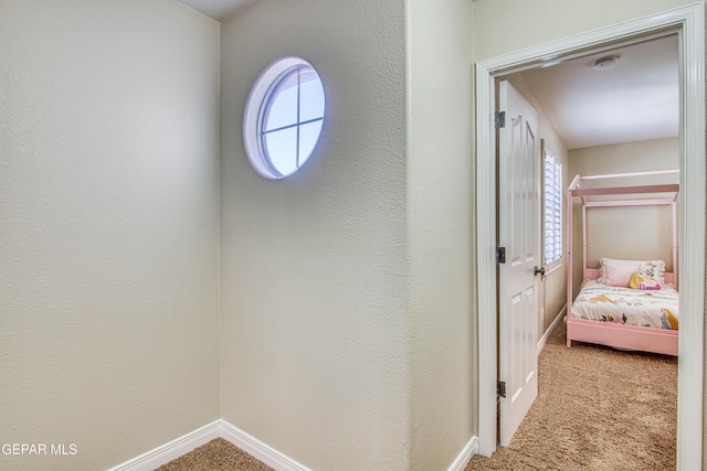 corridor with baseboards and carpet