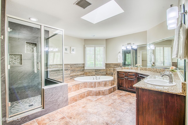 full bath featuring a sink, a skylight, visible vents, a garden tub, and a stall shower