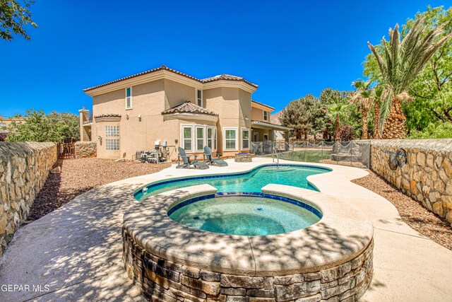 view of pool with a pool with connected hot tub, a fenced backyard, and a patio area