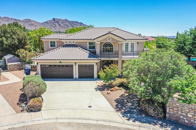 mediterranean / spanish-style house with an attached garage, stucco siding, a balcony, and concrete driveway