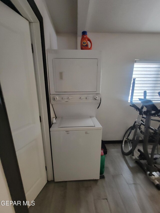 11531 Ernest Rd, Socorro, TX 79927 - laundry area with stacked washer / drying machine, light wood-style flooring, and baseboards