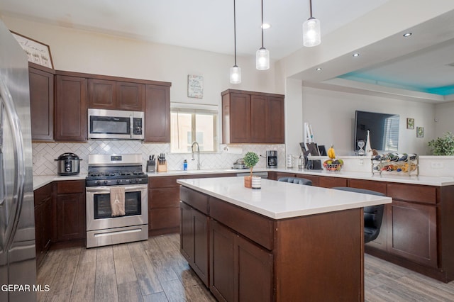 12244 Desert Snow Ct, El Paso, TX 79938 - kitchen featuring a sink, light wood-style floors, backsplash, a peninsula, and appliances with stainless steel finishes