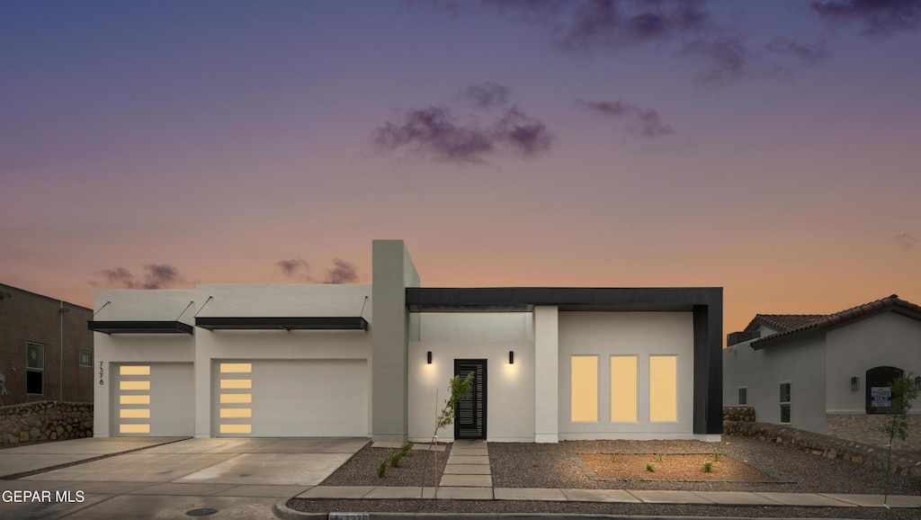 modern home with concrete driveway, a garage, and stucco siding