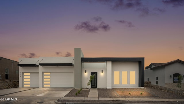 modern home with concrete driveway, a garage, and stucco siding
