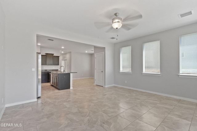 unfurnished living room with a ceiling fan, baseboards, visible vents, and a sink