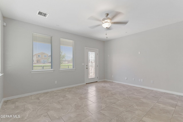 empty room with baseboards, ceiling fan, and visible vents