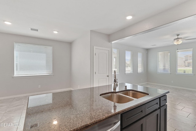 kitchen featuring visible vents, stainless steel dishwasher, a sink, open floor plan, and dark stone counters
