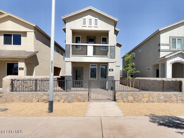 view of front facade featuring a gate, a fenced front yard, stucco siding, and a balcony