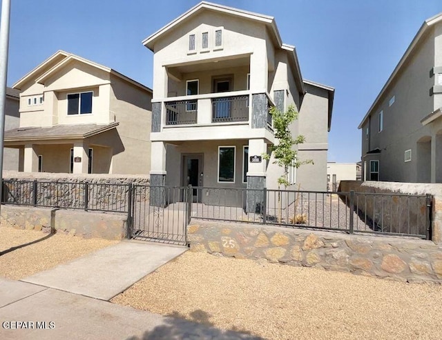 view of front facade featuring a balcony, covered porch, stucco siding, a gate, and a fenced front yard
