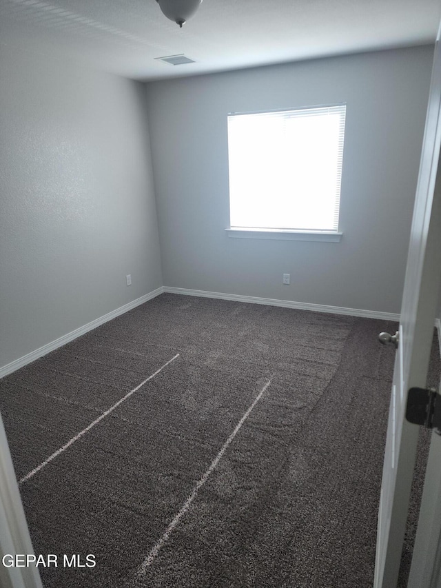 carpeted spare room featuring baseboards and visible vents