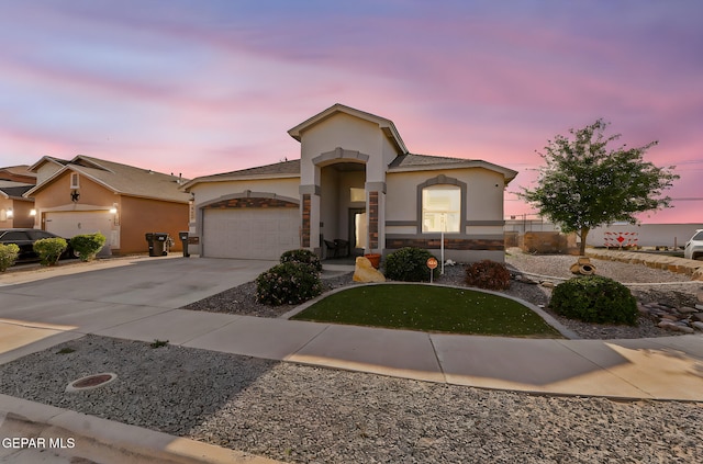 mediterranean / spanish house with a garage, stucco siding, concrete driveway, and stone siding