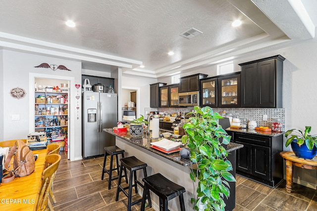 kitchen featuring a breakfast bar area, appliances with stainless steel finishes, an island with sink, and tasteful backsplash