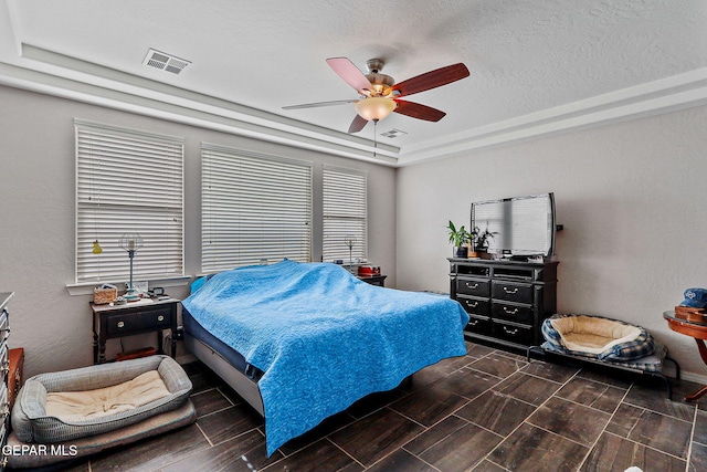 bedroom featuring a raised ceiling, wood tiled floor, a ceiling fan, and visible vents