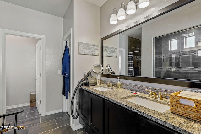 bathroom with double vanity, baseboards, a shower stall, and a sink