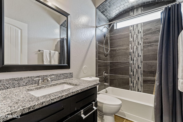 bathroom featuring toilet, a textured wall, shower / bath combo, and vanity