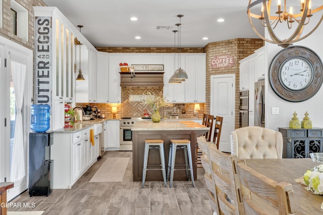 kitchen featuring a chandelier, visible vents, a kitchen island, white cabinetry, and appliances with stainless steel finishes