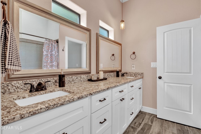 bathroom with baseboards, double vanity, and a sink