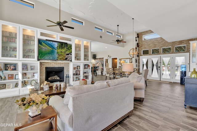 living room with a towering ceiling, a ceiling fan, visible vents, and a fireplace