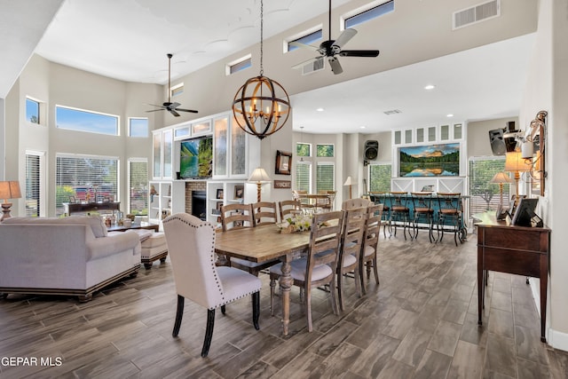 dining area with visible vents, wood finished floors, and ceiling fan with notable chandelier