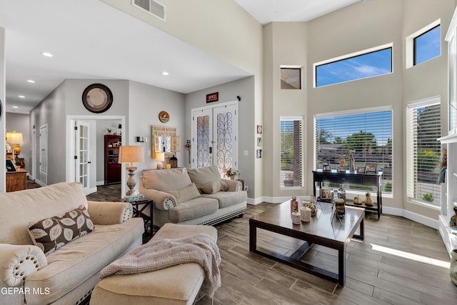 living room featuring visible vents, baseboards, recessed lighting, wood finished floors, and a high ceiling