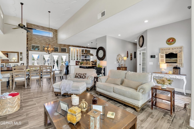 living area featuring ceiling fan with notable chandelier, visible vents, wood tiled floor, and french doors