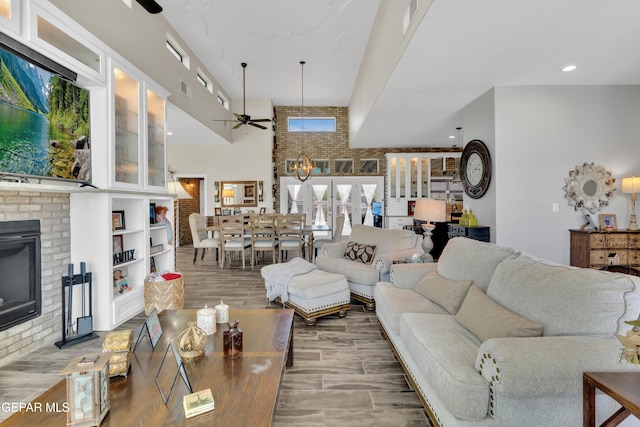living area with brick wall, a fireplace, a ceiling fan, visible vents, and wood finished floors