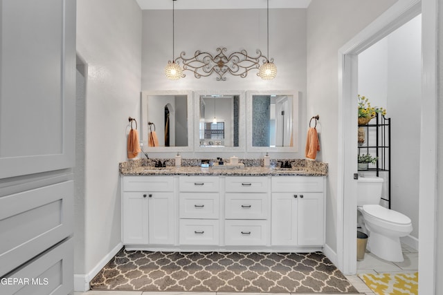 full bath with baseboards, toilet, double vanity, and a sink